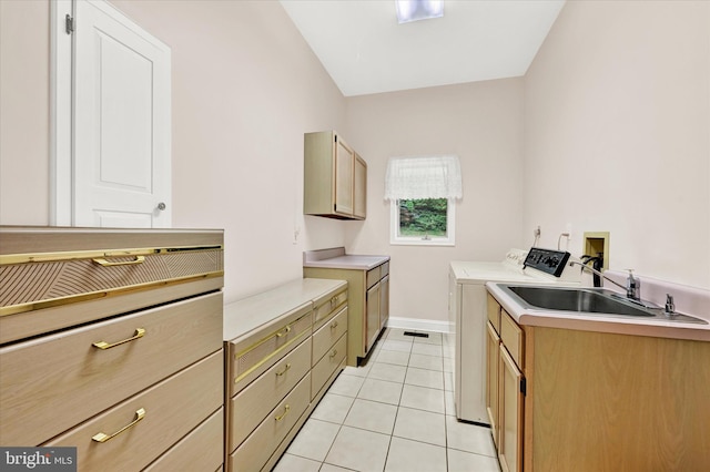 kitchen featuring washer and dryer, sink, and light tile floors