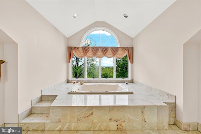 bathroom with lofted ceiling and tiled tub