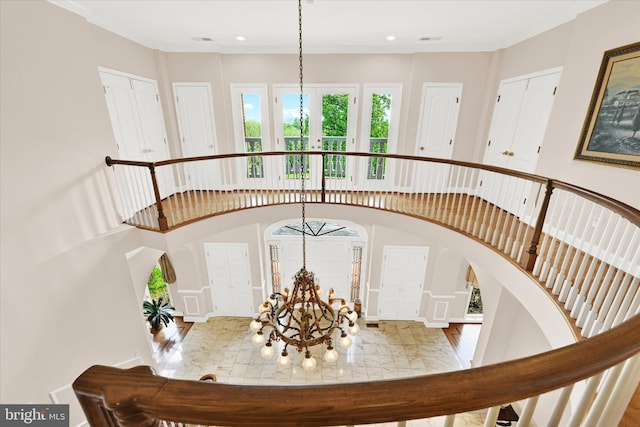 stairway featuring ornamental molding, a notable chandelier, a high ceiling, and hardwood / wood-style flooring