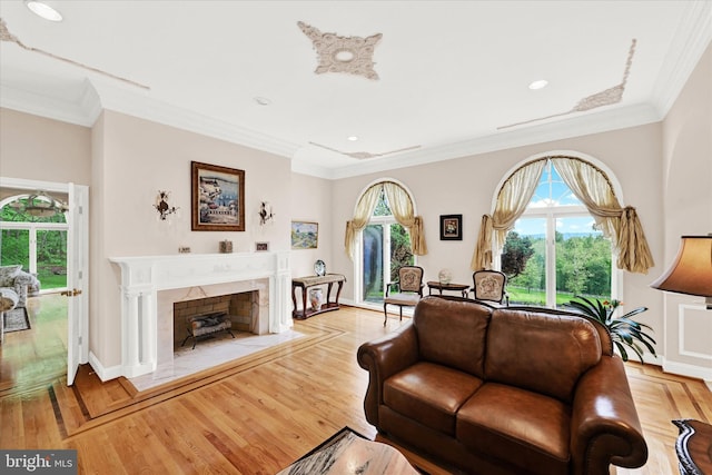 living room with a healthy amount of sunlight, a fireplace, crown molding, and light wood-type flooring