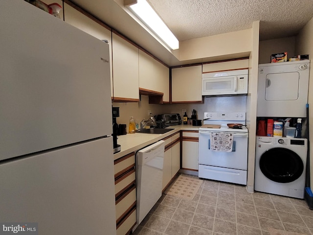 kitchen featuring white appliances, a textured ceiling, stacked washing maching and dryer, sink, and light tile floors