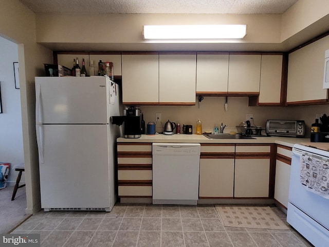 kitchen with white appliances, light tile flooring, a textured ceiling, white cabinetry, and sink