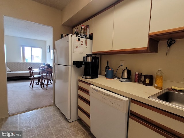 kitchen with white appliances, light tile floors, and white cabinetry