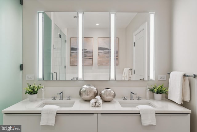 bathroom with a stall shower, a sink, and double vanity