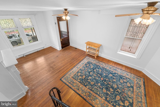 interior space featuring ceiling fan, wood-type flooring, and a baseboard radiator