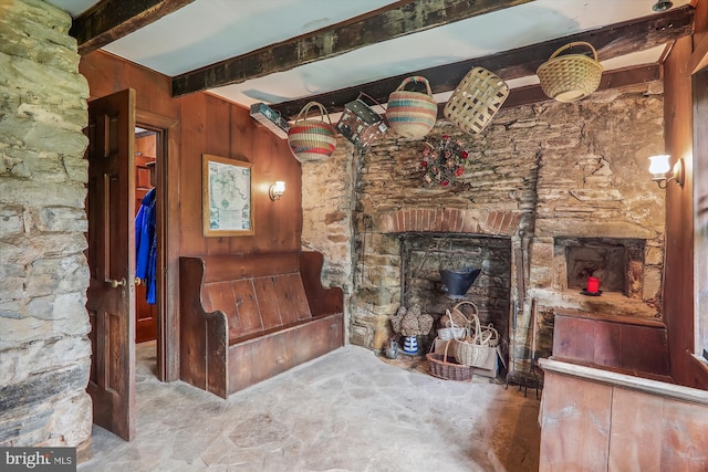 living room with beamed ceiling and wood walls