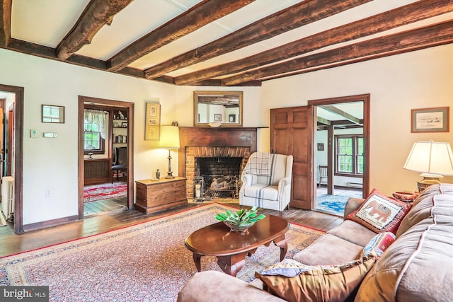 living room featuring a baseboard radiator, beamed ceiling, hardwood / wood-style floors, and a fireplace