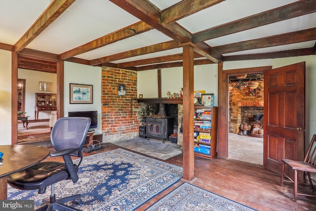 home office with a wood stove, beamed ceiling, and hardwood / wood-style floors