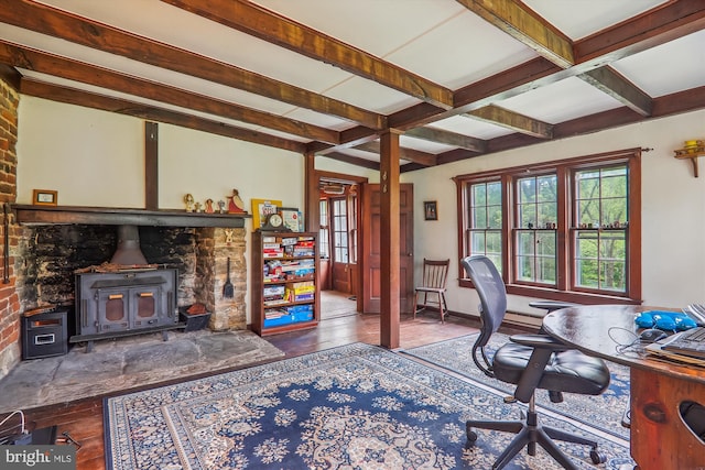 office space featuring beamed ceiling, brick wall, hardwood / wood-style flooring, and a wood stove