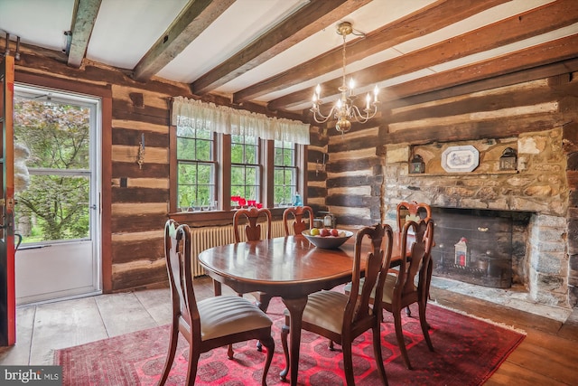 dining area featuring beamed ceiling, a stone fireplace, rustic walls, and an inviting chandelier