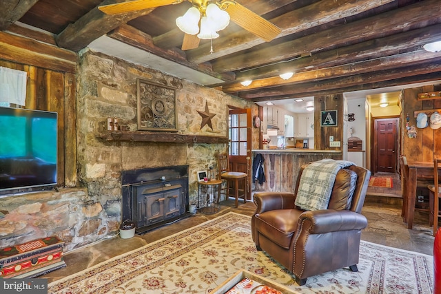 tiled living room featuring a stone fireplace, beam ceiling, and ceiling fan