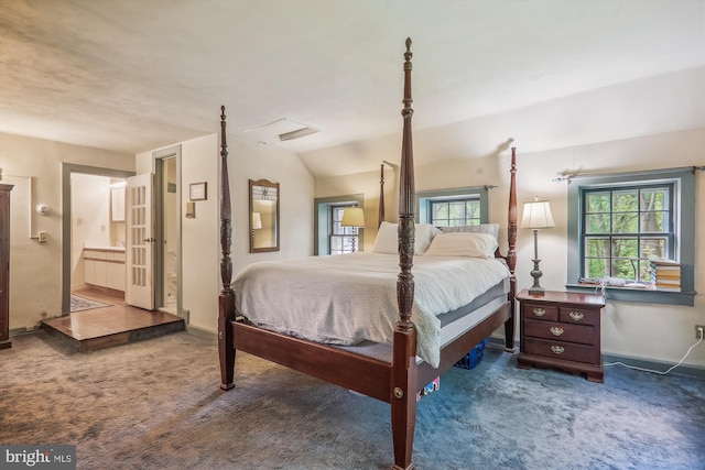 carpeted bedroom featuring lofted ceiling and ensuite bathroom