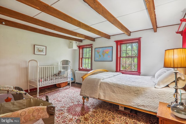 bedroom featuring hardwood / wood-style flooring, radiator heating unit, and beamed ceiling