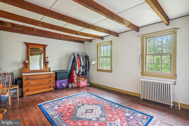 misc room with wood-type flooring, beam ceiling, and radiator