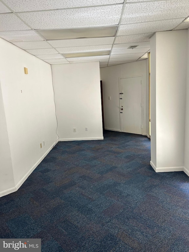 carpeted spare room featuring a drop ceiling