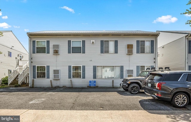 view of front of home with stairs, uncovered parking, and metal roof