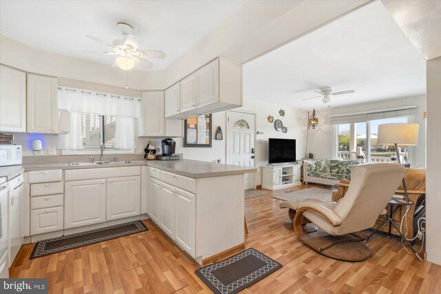 kitchen with a sink, a peninsula, white cabinetry, and ceiling fan