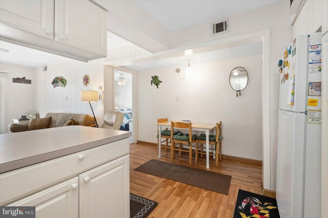 kitchen with visible vents, light wood-style flooring, white cabinets, and freestanding refrigerator