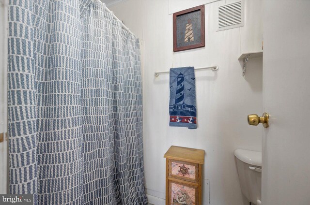 full bath featuring a shower with shower curtain, toilet, and visible vents