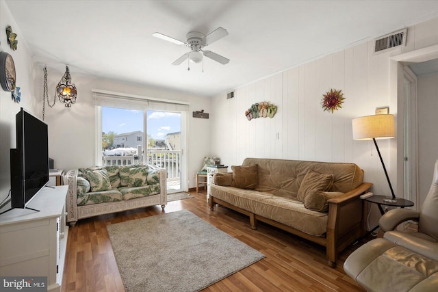 living room featuring wood finished floors, a ceiling fan, and visible vents