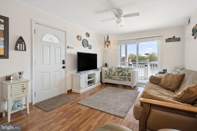 living room with visible vents, wood finished floors, and a ceiling fan