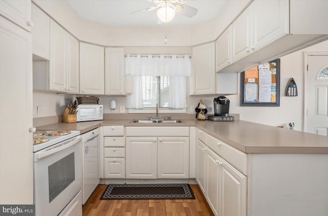 kitchen with ceiling fan, a peninsula, wood finished floors, white appliances, and a sink