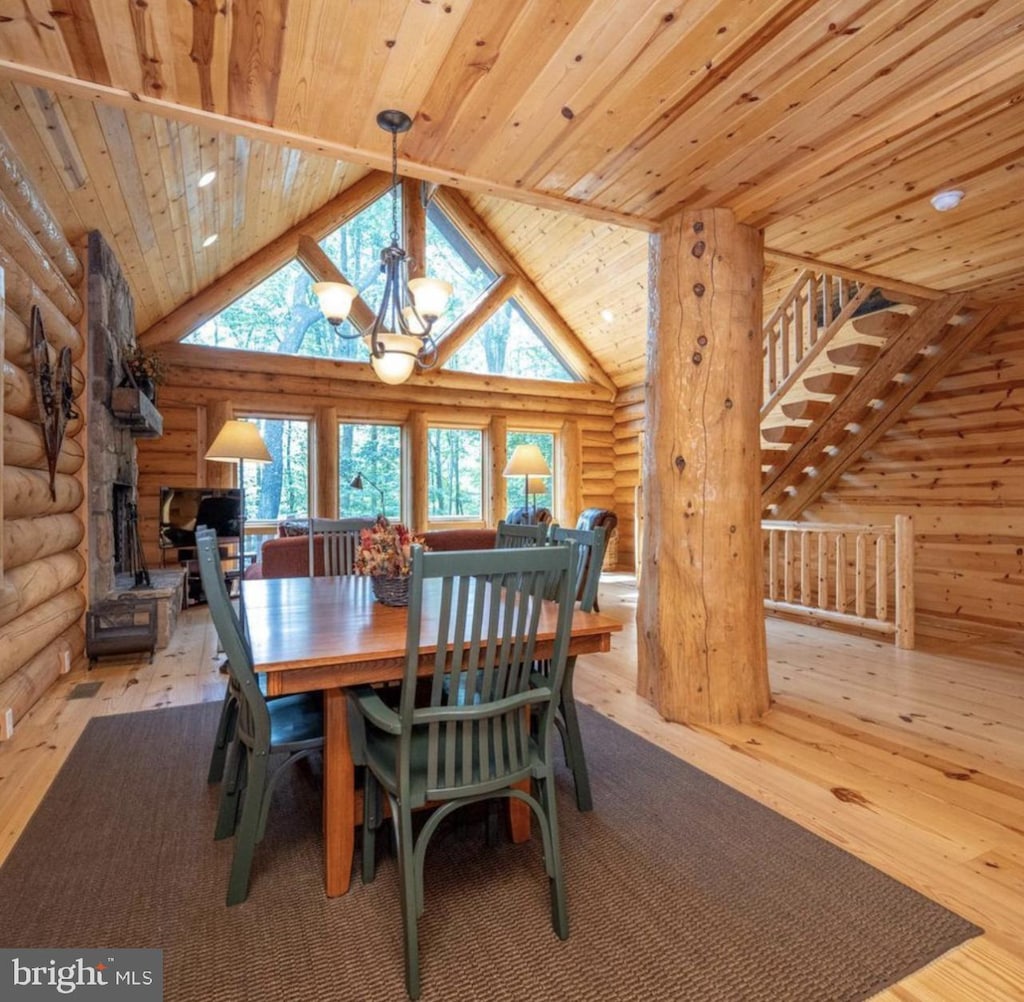 dining space with wooden ceiling, log walls, light wood-type flooring, and a notable chandelier