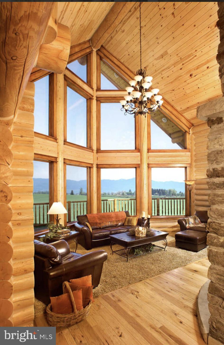 living room with rustic walls, hardwood / wood-style flooring, high vaulted ceiling, beamed ceiling, and a chandelier