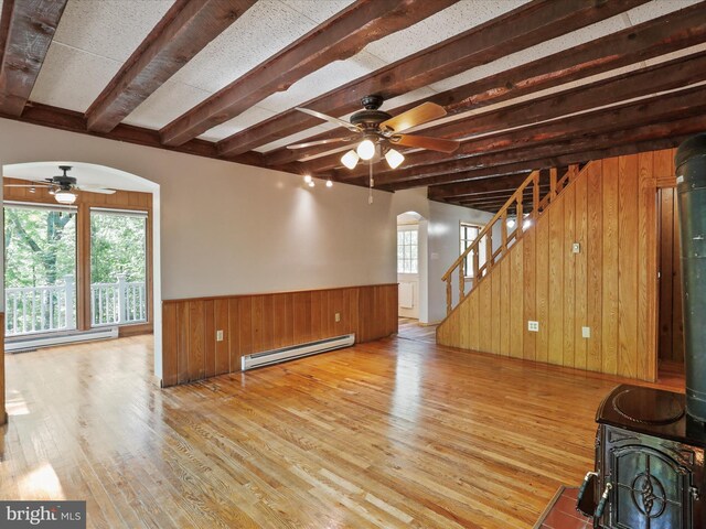 unfurnished living room featuring a baseboard radiator, a wood stove, and light wood-type flooring