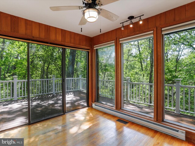 unfurnished sunroom with a baseboard heating unit and ceiling fan