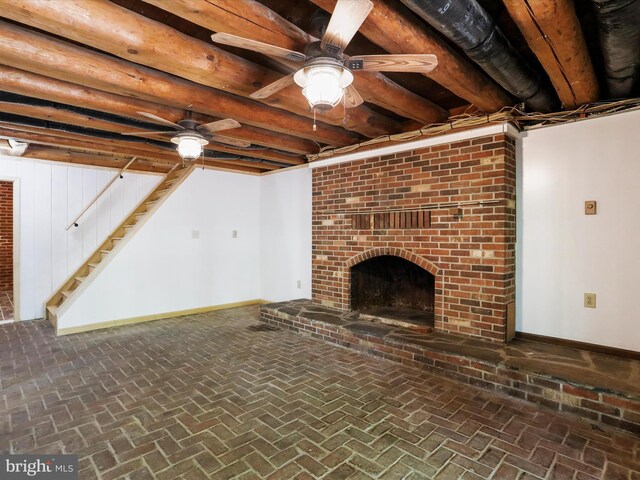 unfurnished living room featuring ceiling fan, beam ceiling, and a brick fireplace