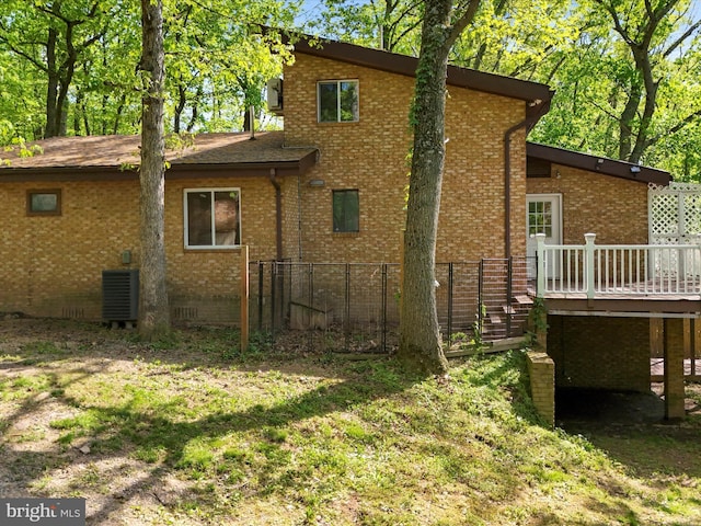 rear view of property with cooling unit, a lawn, and a deck