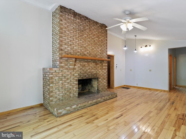 unfurnished living room featuring ceiling fan, a fireplace, ornamental molding, vaulted ceiling, and light wood-type flooring