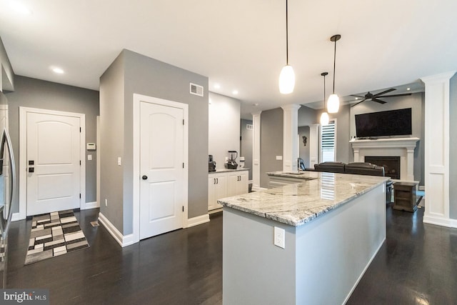 kitchen featuring pendant lighting, decorative columns, dark wood-type flooring, light stone counters, and ceiling fan