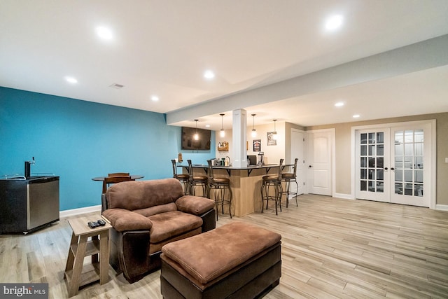 living room featuring ornate columns, light hardwood / wood-style flooring, and french doors