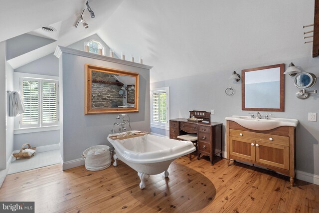 bathroom featuring a bathing tub, track lighting, lofted ceiling, vanity, and hardwood / wood-style flooring