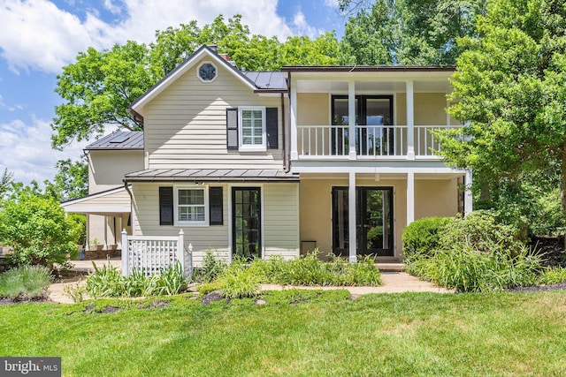 back of house featuring a porch, a balcony, and a yard