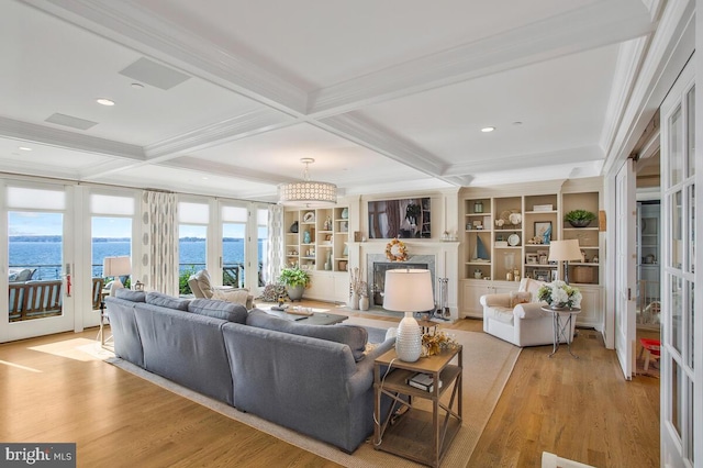 living room featuring a premium fireplace, beamed ceiling, a water view, light hardwood / wood-style flooring, and coffered ceiling