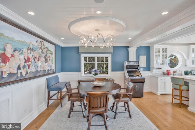 dining space featuring an inviting chandelier, ornamental molding, and light wood-type flooring