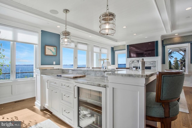 kitchen with white cabinets, light wood-type flooring, a water view, and wine cooler