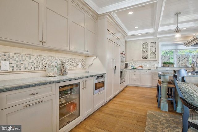 kitchen with light hardwood / wood-style floors, appliances with stainless steel finishes, wine cooler, light stone countertops, and crown molding