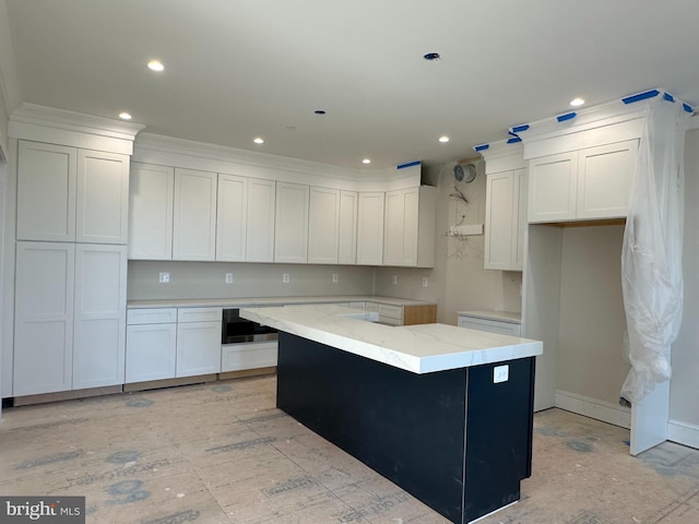 kitchen featuring a kitchen island, white cabinets, and light stone countertops