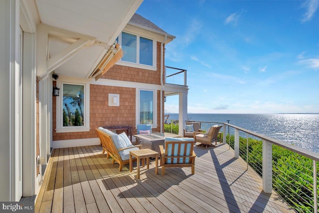 wooden terrace featuring a water view and an outdoor living space with a fire pit