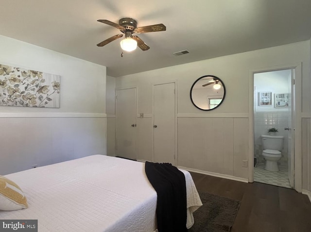 bedroom featuring dark hardwood / wood-style floors, connected bathroom, ceiling fan, and tile walls