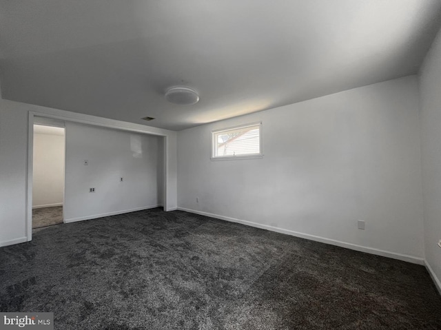 spare room with dark colored carpet