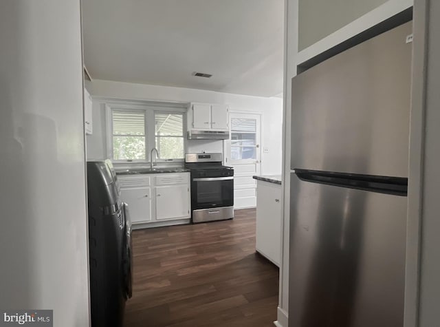 kitchen featuring appliances with stainless steel finishes, dark stone counters, white cabinetry, sink, and dark hardwood / wood-style flooring