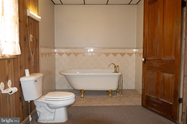 bathroom with a bathing tub, tile patterned flooring, and tile walls