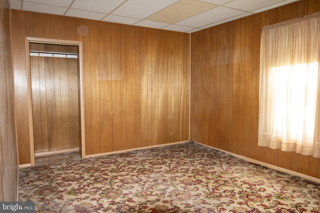 spare room with a paneled ceiling and wooden walls