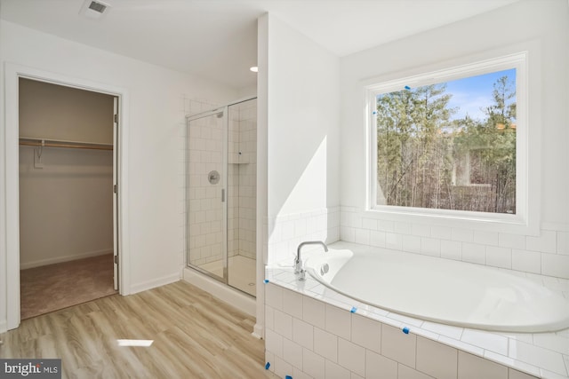 bathroom with wood-type flooring and shower with separate bathtub