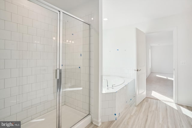 bathroom with wood-type flooring and shower with separate bathtub